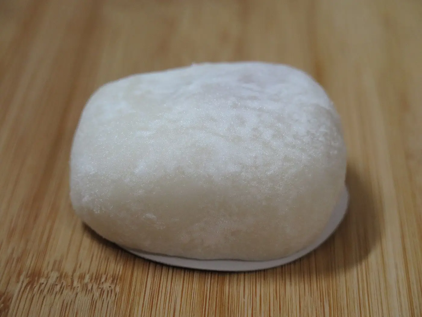 A whole white daifuku on a wooden board