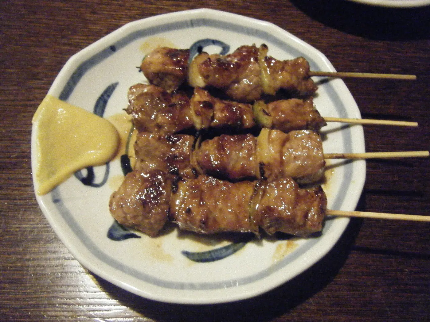 Glazed chicken meatball skewers with mustard on a blue and white plate